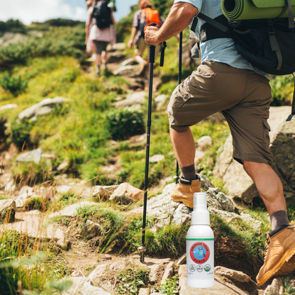 Person hiking on a trail with a bottle of FURIE Hand & Skin spray in the on a rock